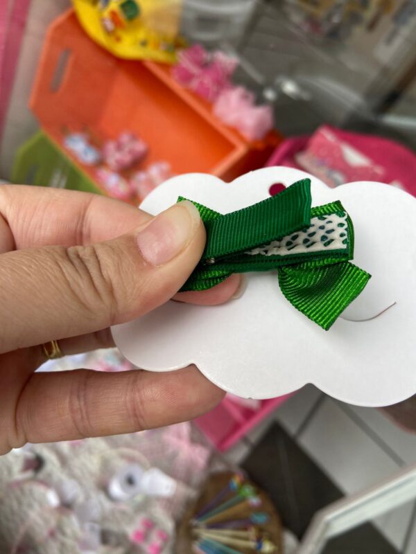 Mini Laço verde parte de trás do laço onde mostra o bico de pato encapado com o forro anti-deslizante que protege a cabeça do bebê.