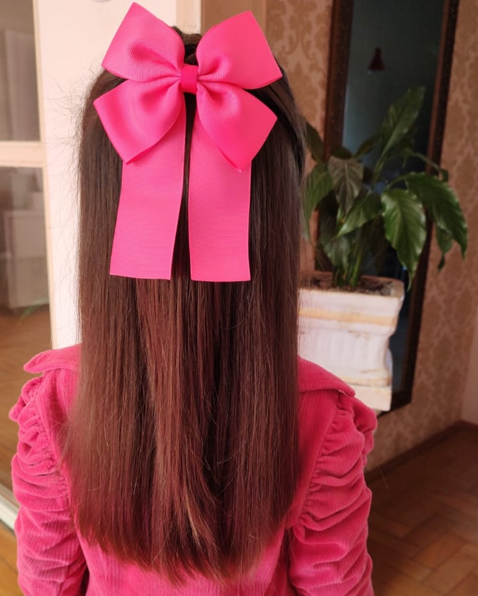 Menina usando um laço rosa com pontas.